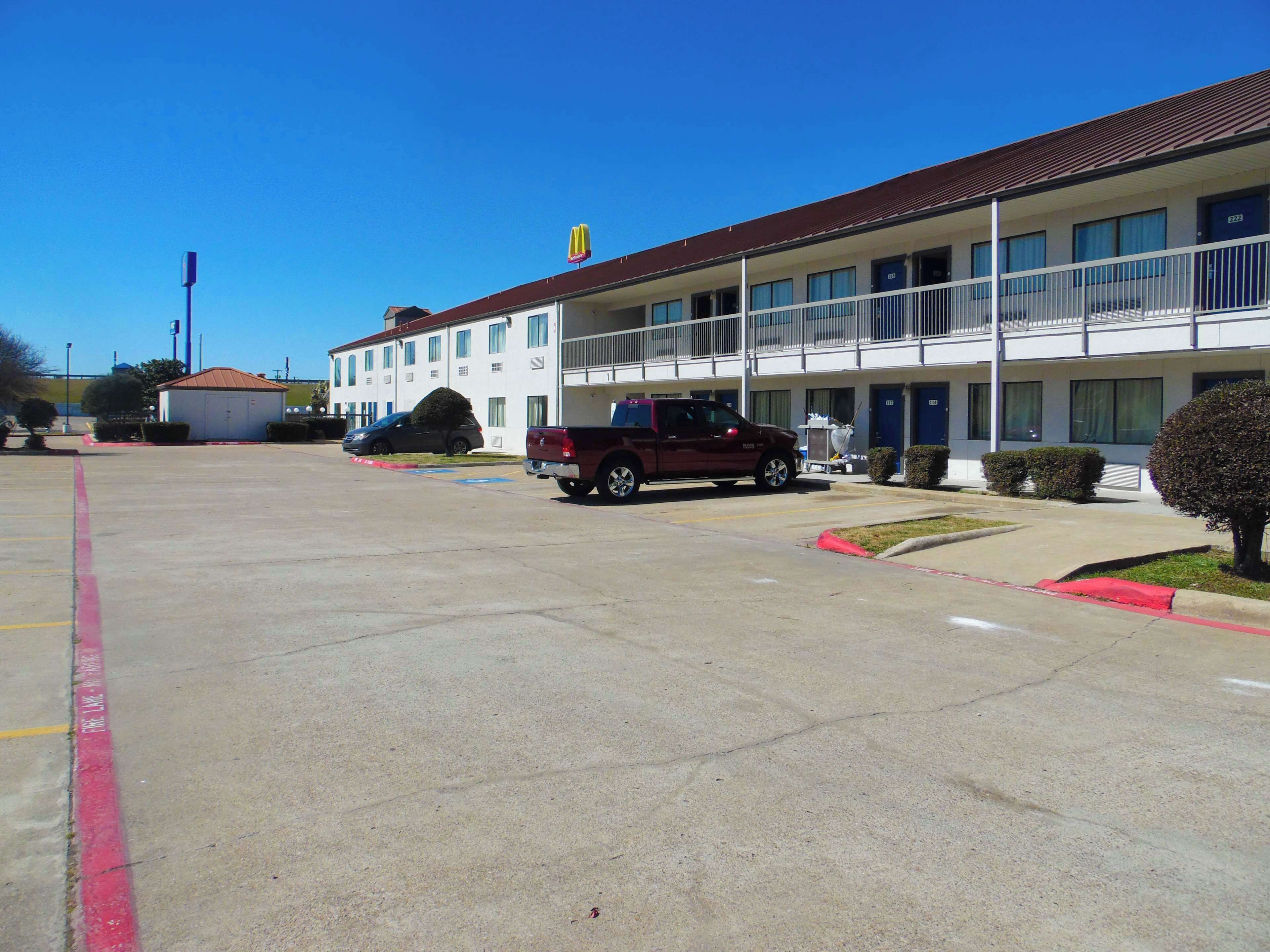 A motel with a parking lot, a red pickup truck, and a McDonald's sign.