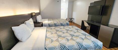A hotel room with two beds, a desk, a television, and a chair.