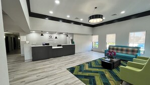 A modern reception area with a reception desk, a sofa, and a patterned rug. - Quality Inn & Suites at Airport Blvd I-65 (Mobile)