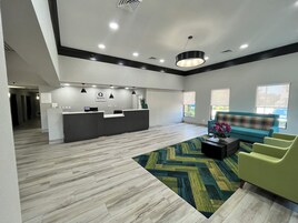 A modern reception area with a reception desk, a sofa, and a patterned rug.