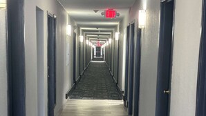 A long, narrow hotel corridor with doors on both sides and a carpeted floor. - Quality Inn & Suites at Airport Blvd I-65 (Mobile)