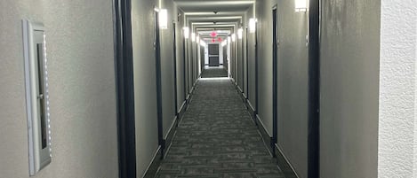 Un largo y estrecho pasillo de hotel con pisos alfombrados y puertas a ambos lados.