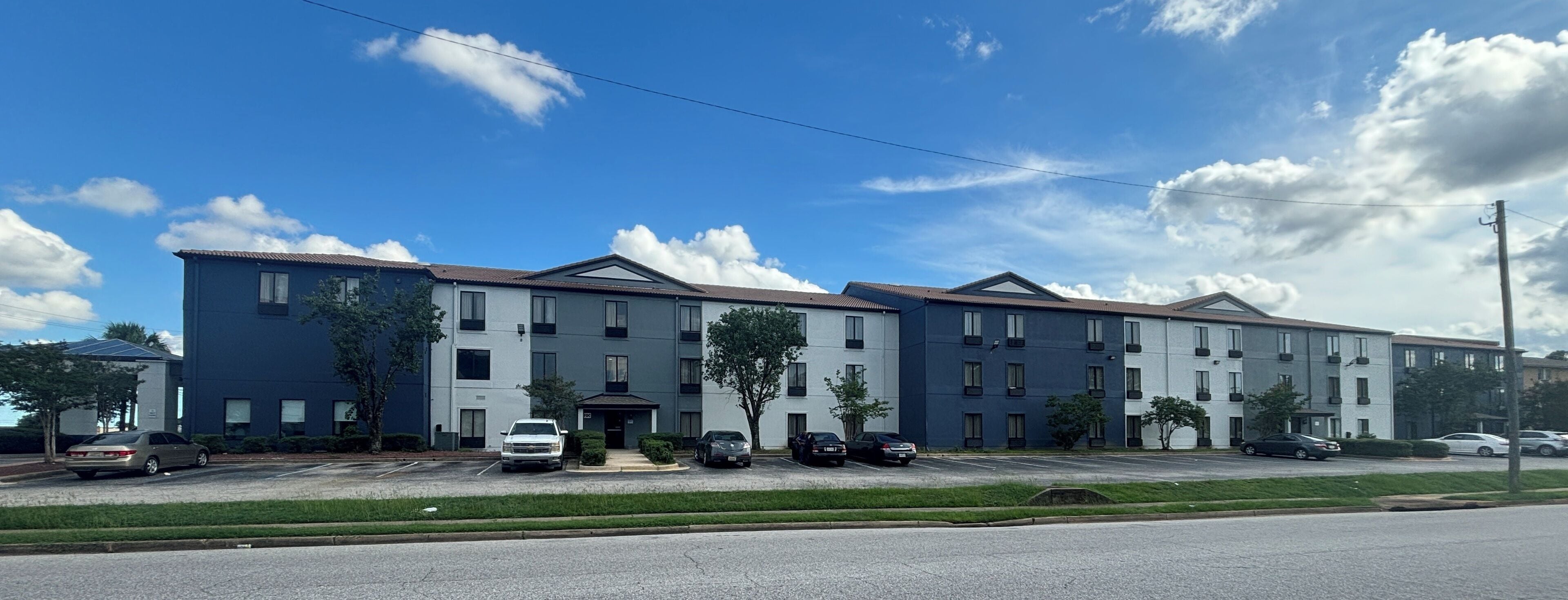 A multi-story residential building with a parking lot in front.