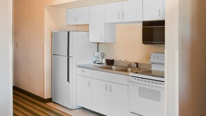 Una cocina funcional con armarios blancos, un refrigerador, una estufa y un microondas.