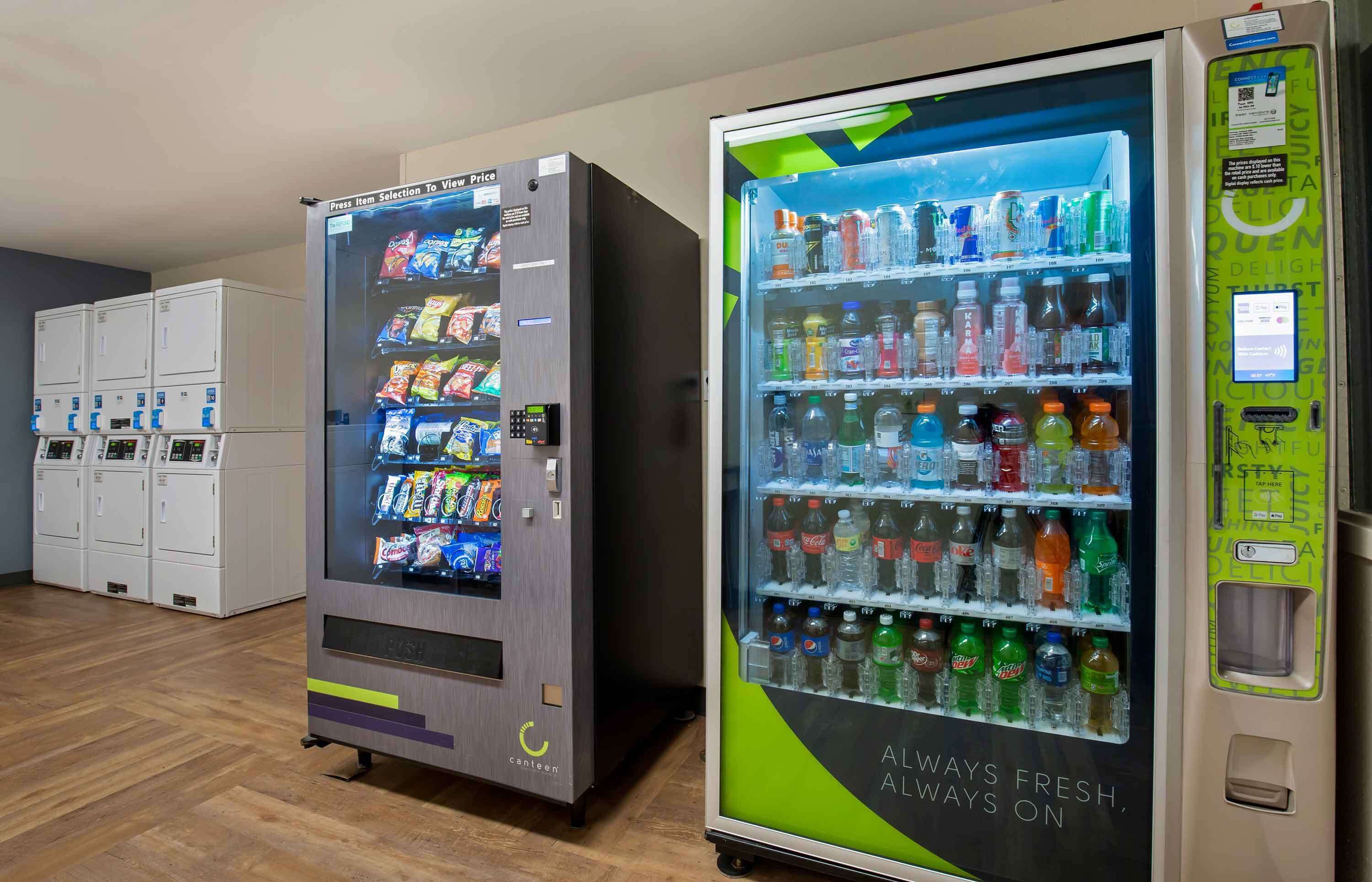 Two vending machines with snacks and drinks, and a row of lockers in the background.