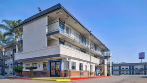 A multi-story motel with a flat facade, a 'Welcome' sign, and a '6' sign indicating the motel's name.