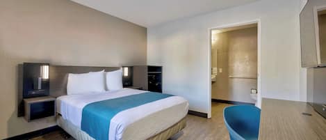 Una habitación de hotel con cama, mesitas de noche, escritorio y silla.