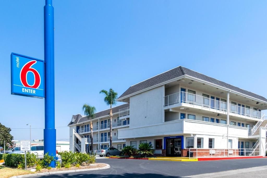 A motel with a prominent blue '6 ENTER' sign, a multi-story building with balconies, and a parking area.