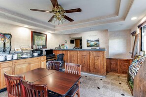 A spacious kitchen with wooden cabinets, a dining table with chairs, a ceiling fan, and a kitchen island with a sink and microwave. - Knights Inn Madera (Madera)
