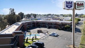 Un hotel con piscina, aparcamiento y letreros de Knights Inn y Perkins.