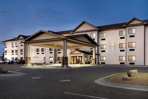 Un hotel de varios pisos con un acceso cubierto y zona de estacionamiento.