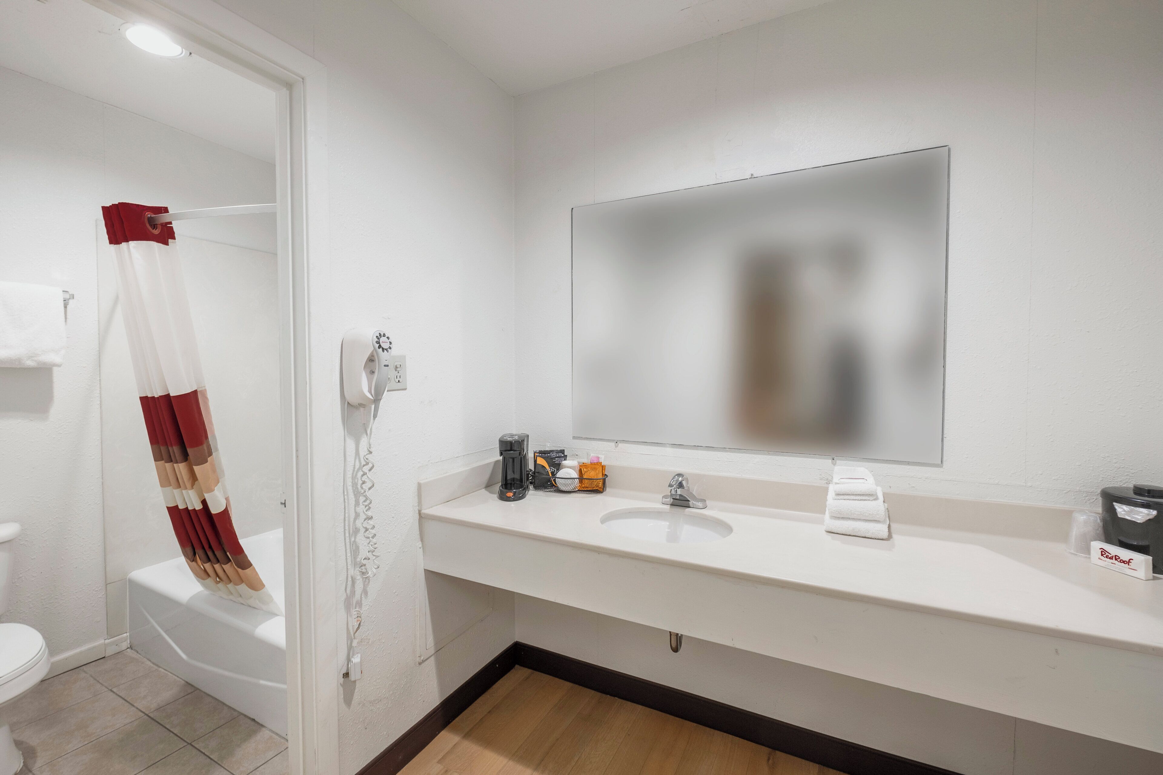 Un baño con lavamanos blanco, un espejo, toallero, cortina de ducha y un inodoro.