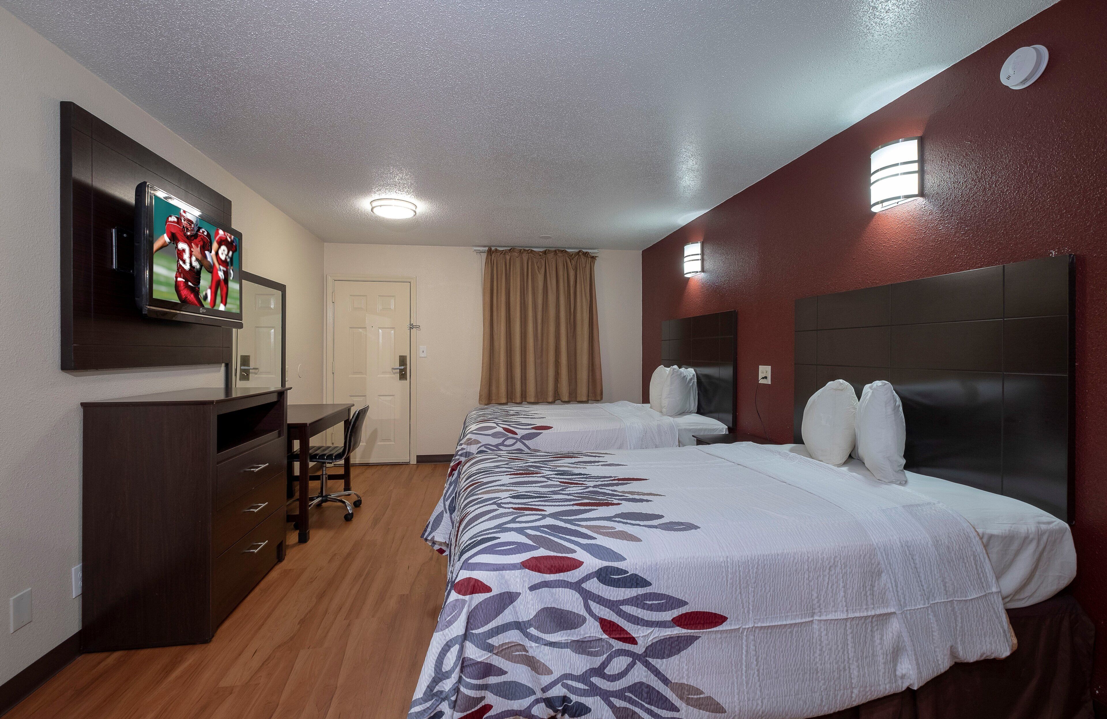 A hotel room with a bed, a desk, and a television on the wall.