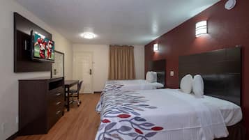 A hotel room with a bed, a desk, and a television on the wall.