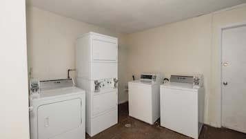 A laundry room with two stacked washers and dryers, a door, and a wall-mounted control panel.