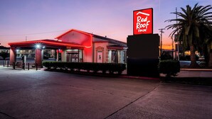 A Red Roof Inn with a red neon sign, a brick facade, and a parking lot. - Red Roof Inn Morgan City (Morgan City)