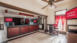 A hotel lobby with a reception desk, a ceiling fan, and a sign indicating free Wi-Fi in all rooms. - Red Roof Inn Morgan City (Morgan City)