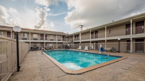 A courtyard with a swimming pool, outdoor seating, and a multi-story building with balconies. - Red Roof Inn Morgan City (Morgan City)