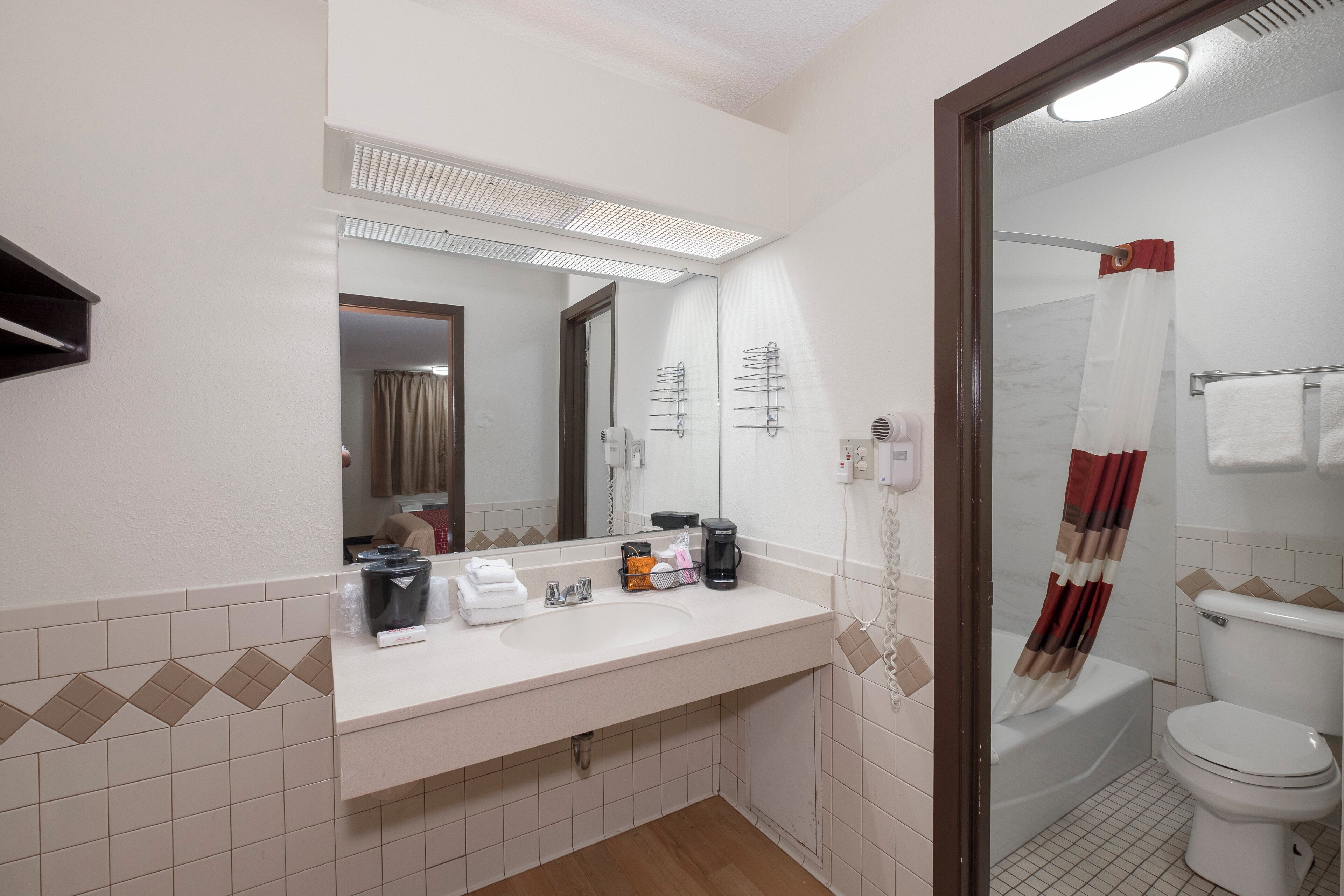 Un baño con lavamanos blanco, espejo y zona de ducha.
