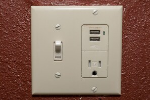 A wall-mounted electrical outlet with a switch and two USB ports, set against a textured wall. - Red Roof Inn Morgan City (Morgan City)