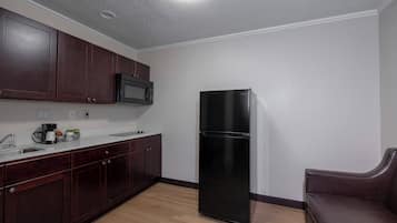 A kitchen with dark wooden cabinets, a black refrigerator, and a microwave.