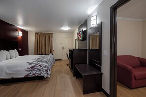 A hotel room with a bed, a desk, a TV, and a red chair. - Red Roof Inn Morgan City (Morgan City)