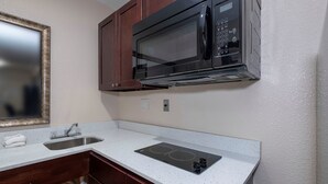 A compact kitchenette with a microwave, a sink, and a stovetop. - Red Roof Inn Morgan City (Morgan City)