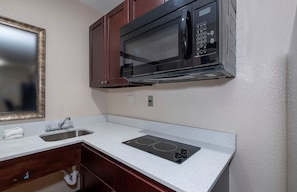 A compact kitchenette with a microwave, a sink, and a stovetop. - Red Roof Inn Morgan City (Morgan City)