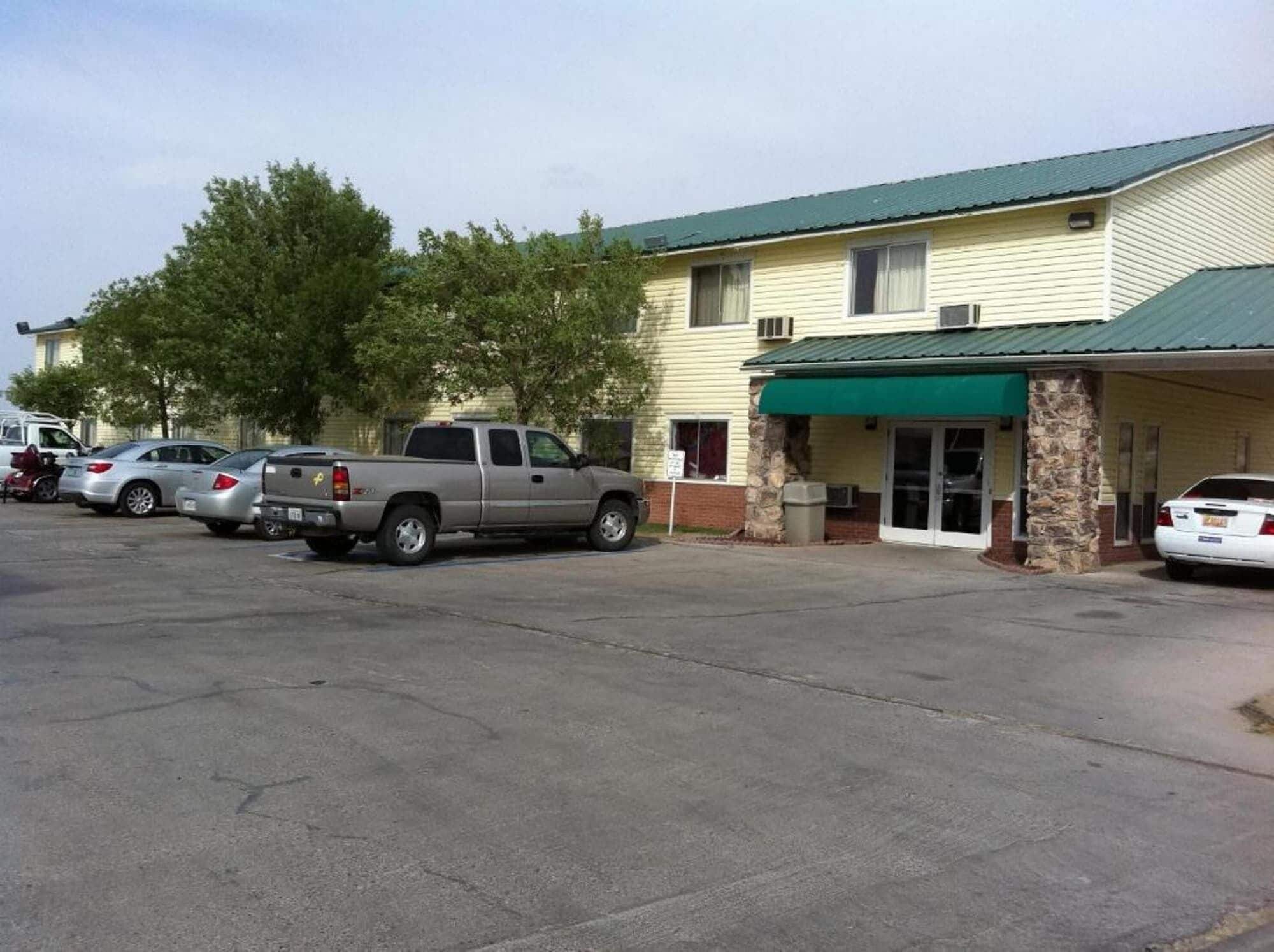 A building with a green awning and a parking lot with several cars.