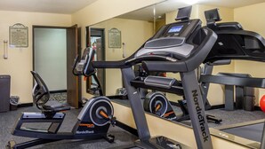 Un gimnasio con cintas de correr, una máquina elíptica y una bicicleta estática.
