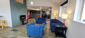 A hotel lobby with a fireplace, blue sofas, a wooden floor, and a window with a view.