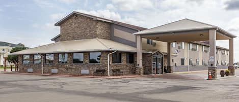 A two-story building with a stone facade and a covered entrance area.