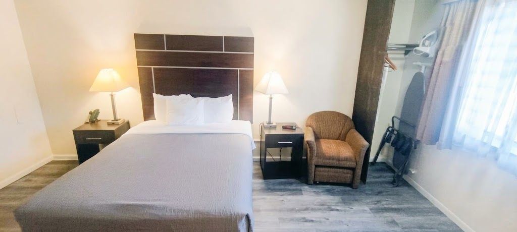 A hotel room with a bed, two bedside tables with lamps, a chair, and a television.