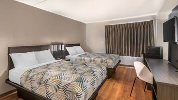 A hotel room with two beds, a desk, a chair, a television, and a window with curtains.