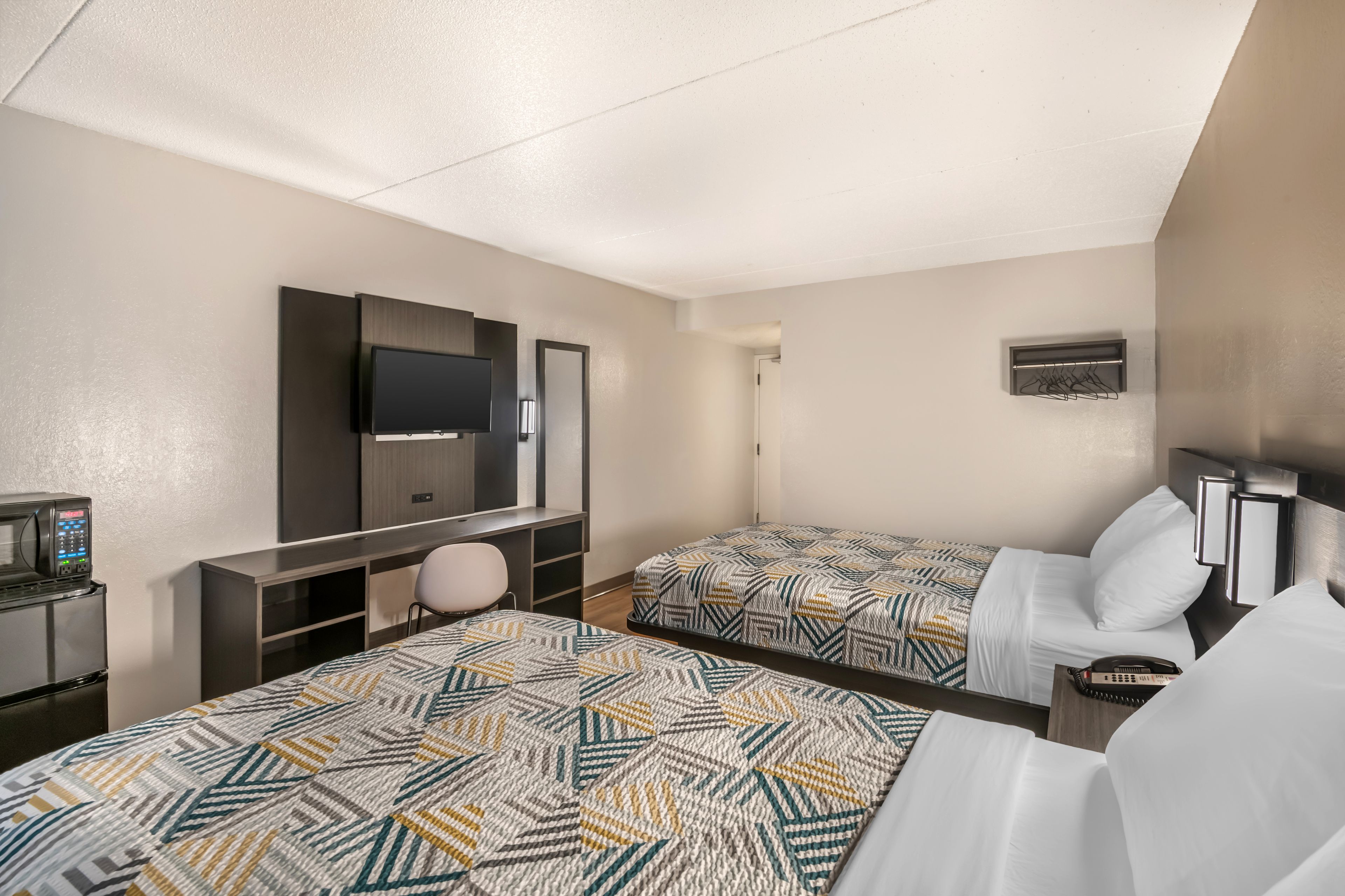 Une chambre d’hôtel avec deux lits, un bureau, une télévision et un four à micro-ondes.