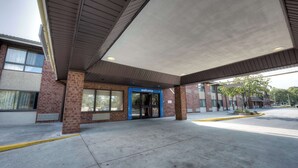 A building entrance with a 'welcome' sign, a covered area, and a clear sidewalk.
