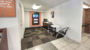 A hotel lobby with a check-in counter, seating area, and a television screen.