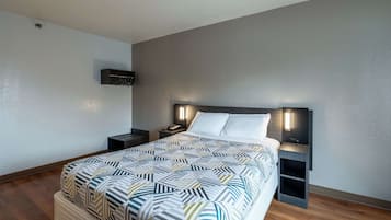 Une chambre d’hôtel moderne avec un grand lit, un téléviseur à écran plat fixé au mur, des lampes de chevet et une petite table de chevet.