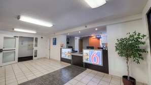 A hotel reception area with a reception desk, a potted plant, and a sign indicating room number 6.