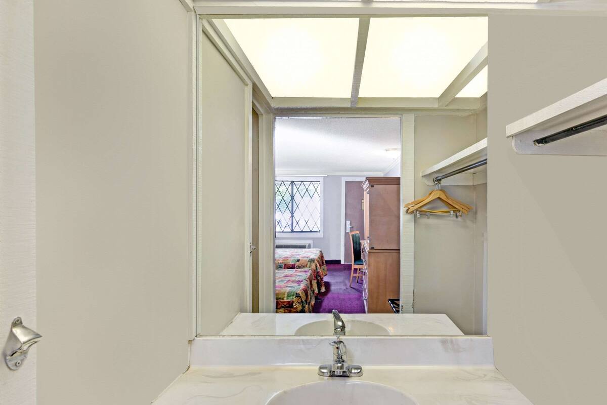 A bathroom with a large mirror, a sink, and a window above the mirror.