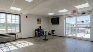 A spacious room with a large window, a flat-screen TV mounted on the wall, and a small table with two chairs. - Motel 6 White, GA - Cartersville (White)