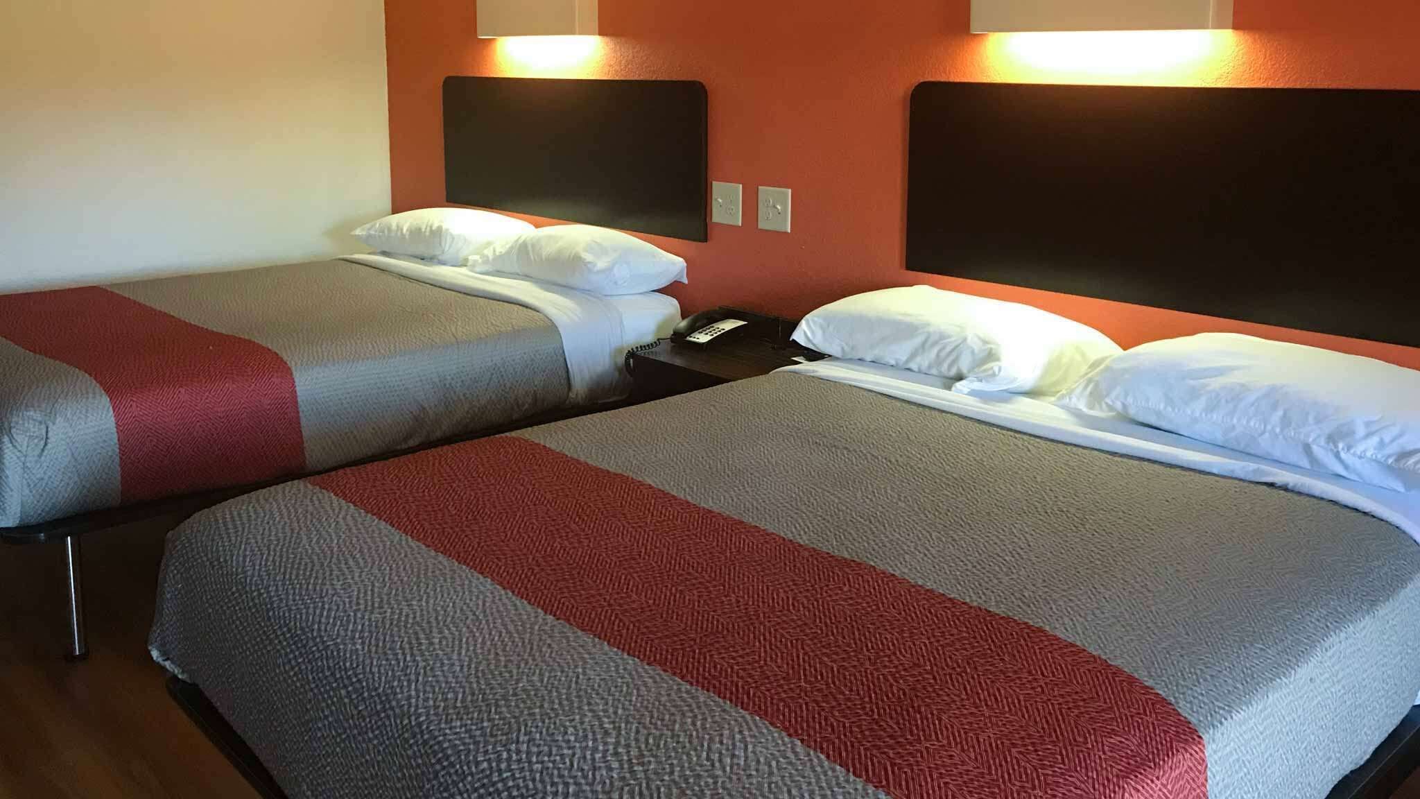 Two single beds with headboards, a bedside phone, and a wall socket.