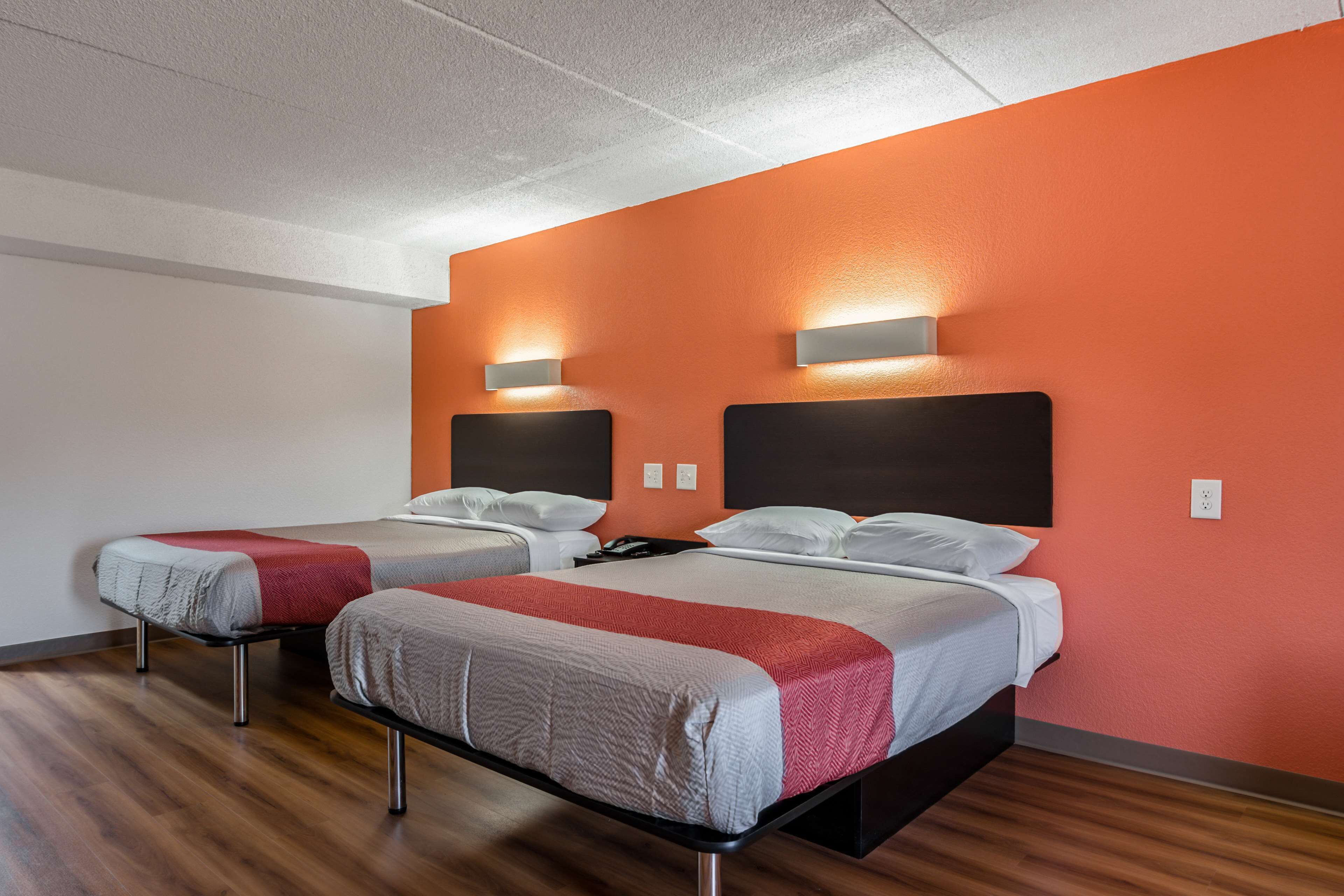 Une chambre d’hôtel avec deux lits, chacun doté d’une tête de lit et de tables de chevet, et un plancher en bois.