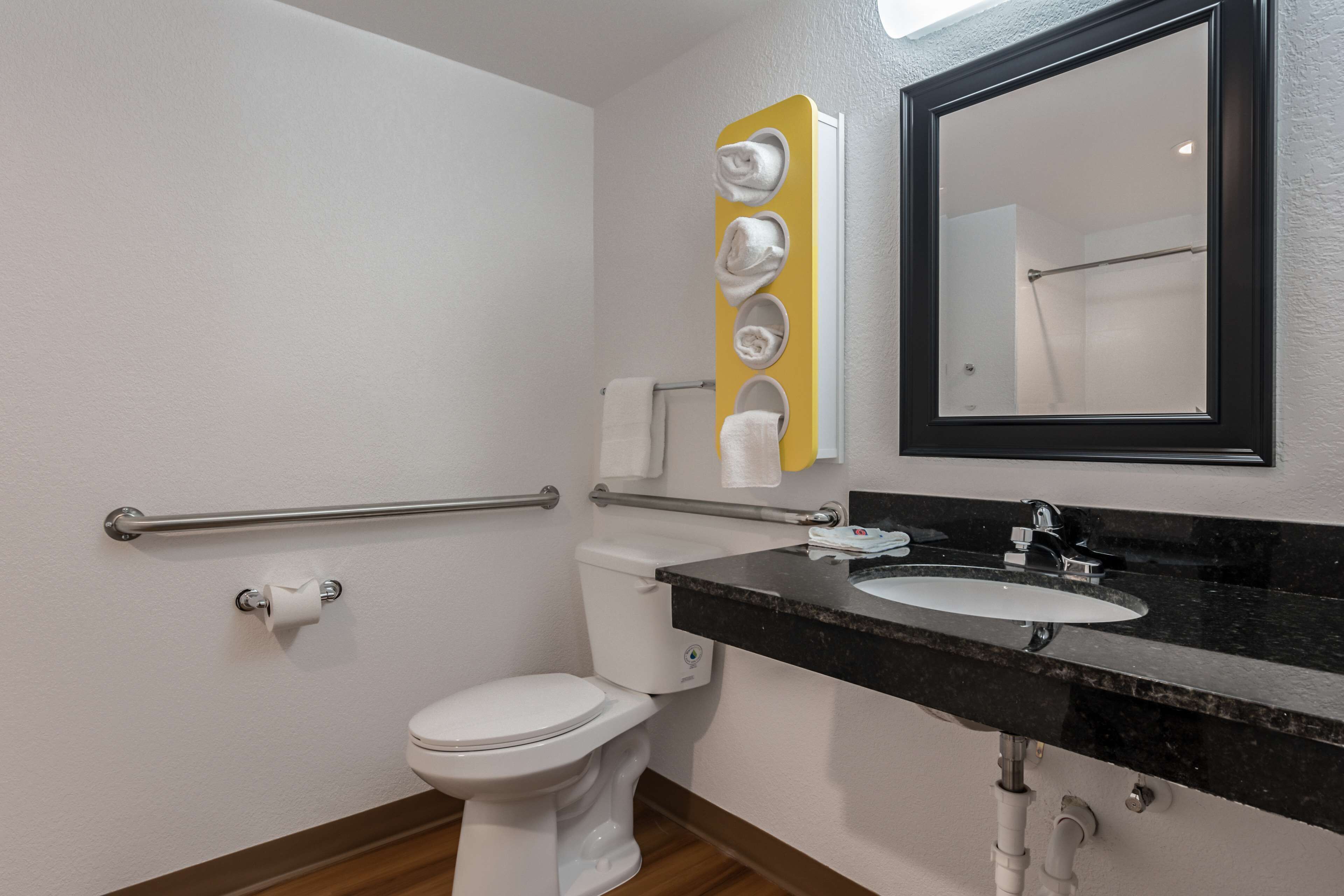 A bathroom with a white toilet, a black sink, and a mirror.