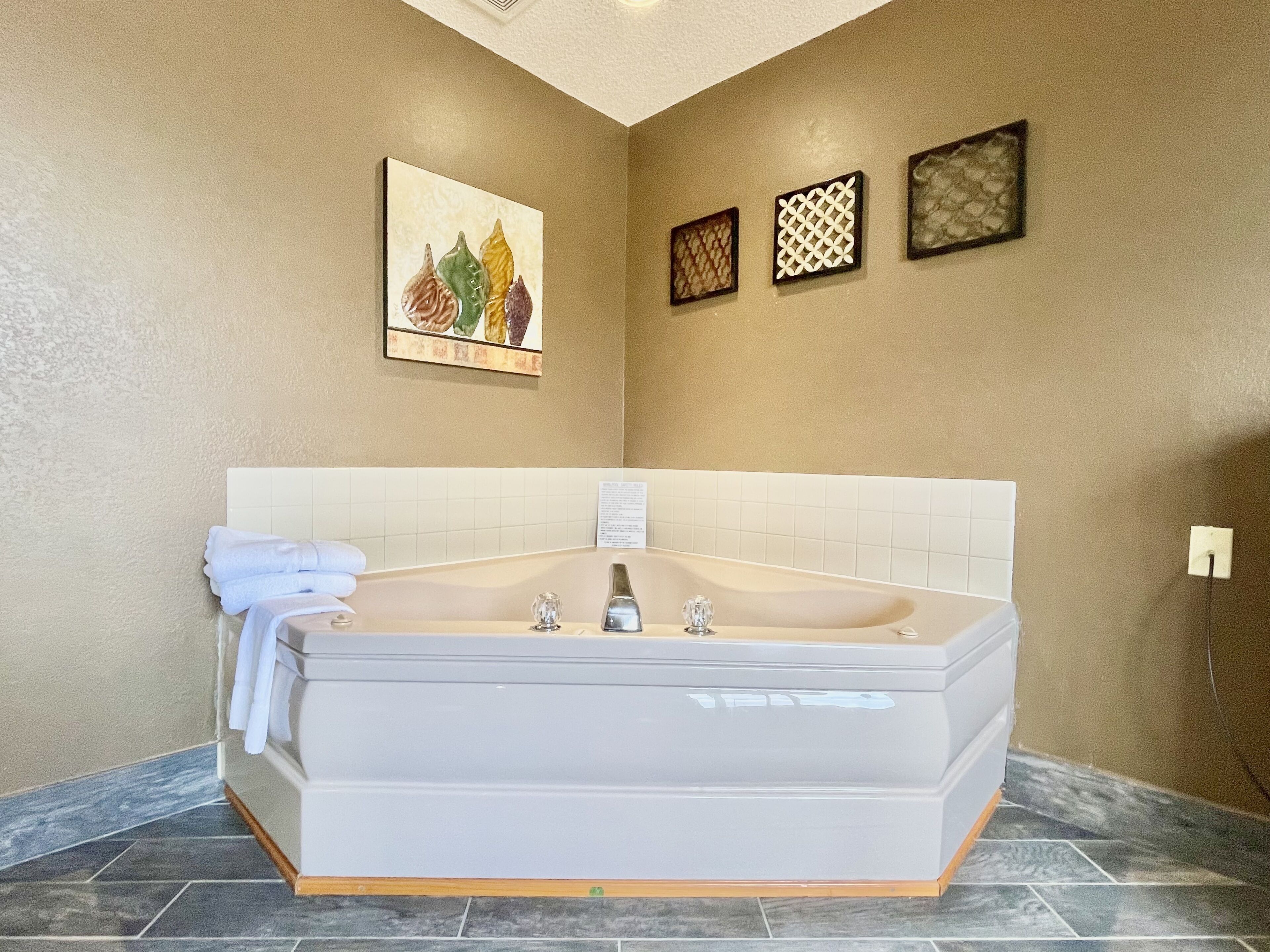 A modern bathroom with a large bathtub, a wall-mounted towel rack, and decorative wall art.
