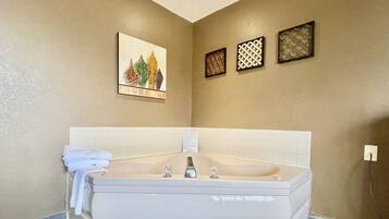 A modern bathroom with a large bathtub, a wall-mounted towel rack, and decorative wall art.