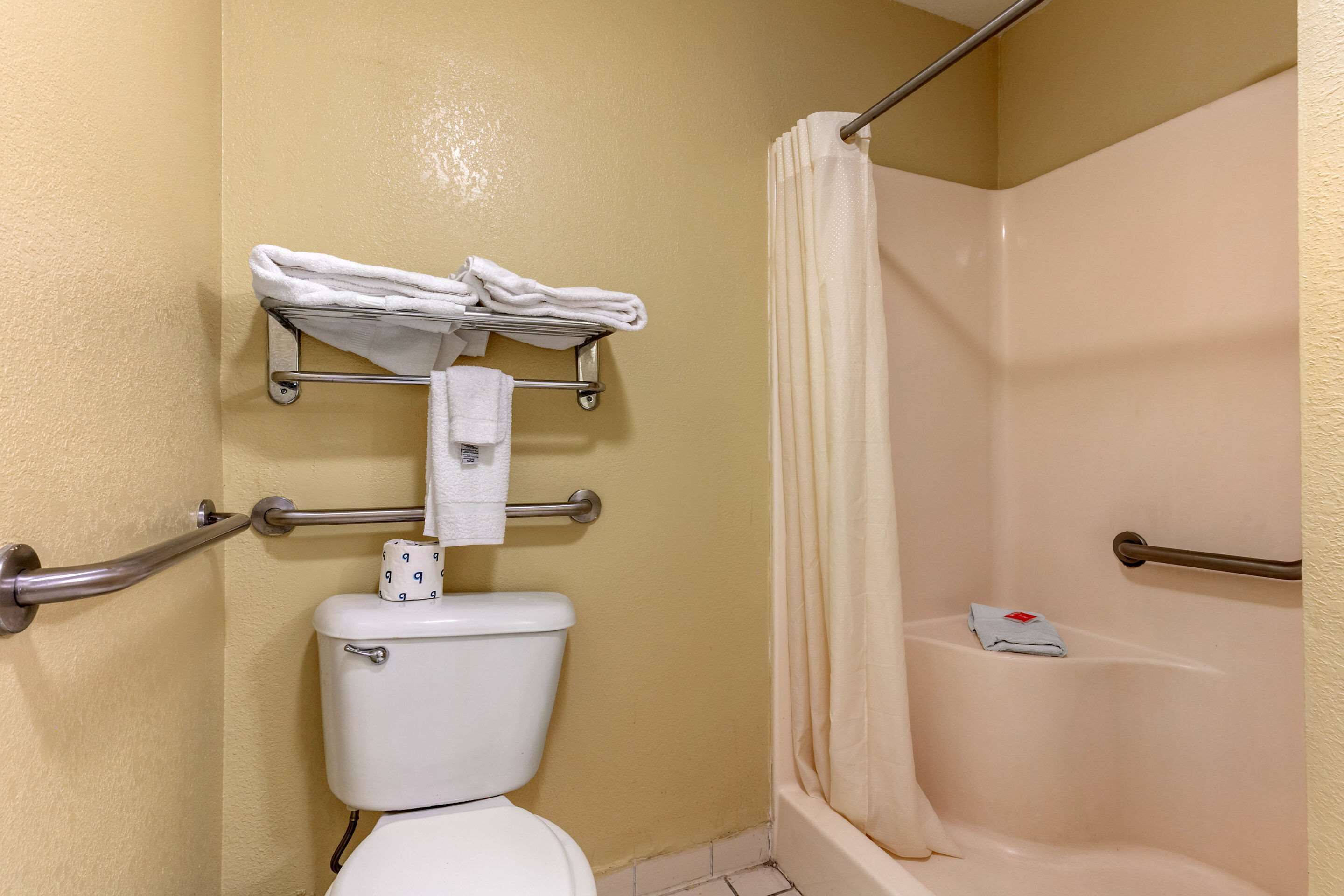 Een badkamer met toilet, douche met gordijn en een handdoekrek met handdoeken.