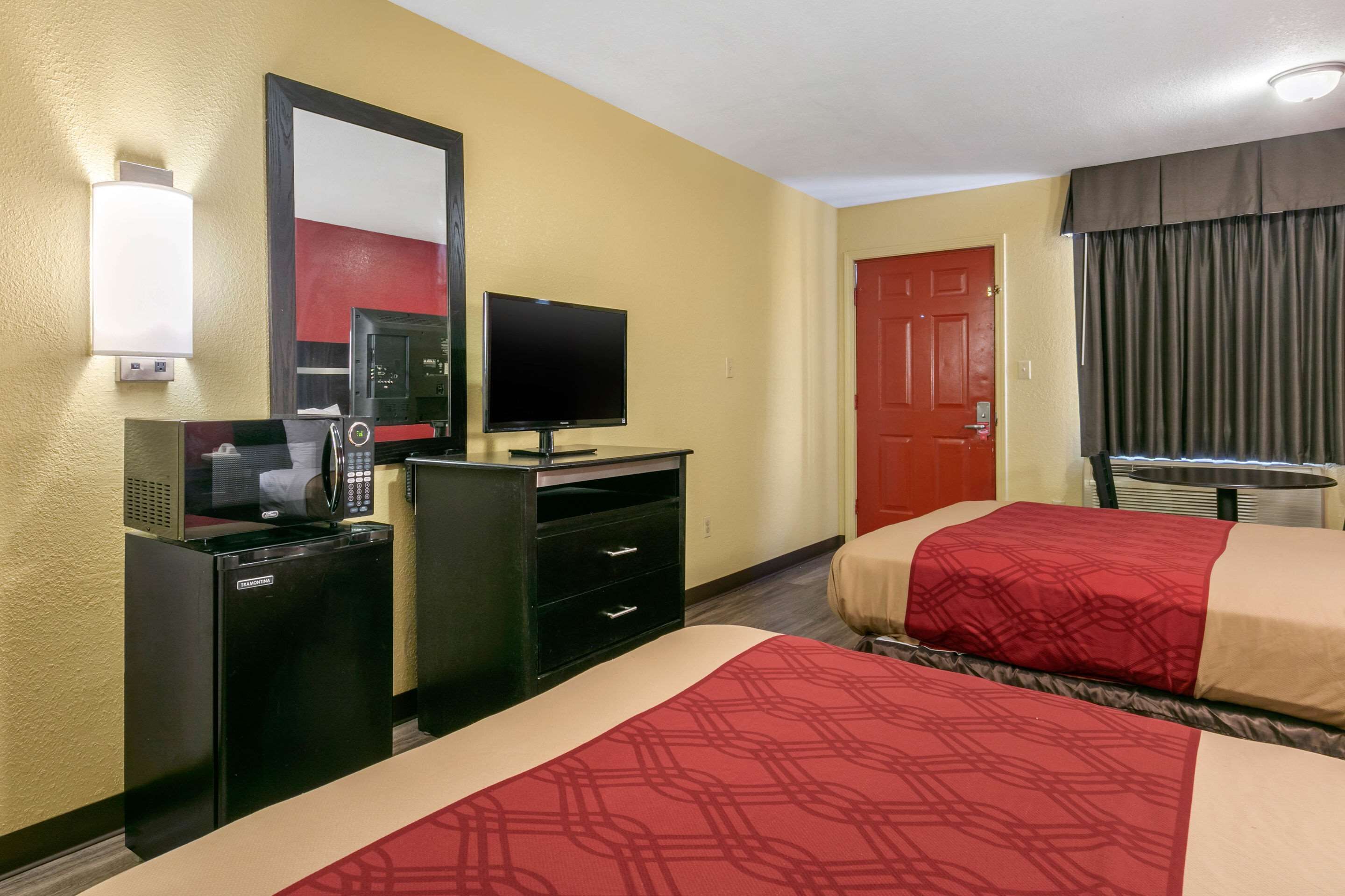 Une chambre d’hôtel avec deux lits, une télévision, un bureau avec un micro-ondes et une porte.