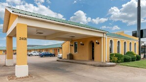 A yellow building with a covered entrance and numbered columns, likely a motel or hotel.