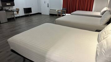 Quarto de hotel com duas camas, uma escrivaninha, uma cadeira, uma televisão e uma porta.